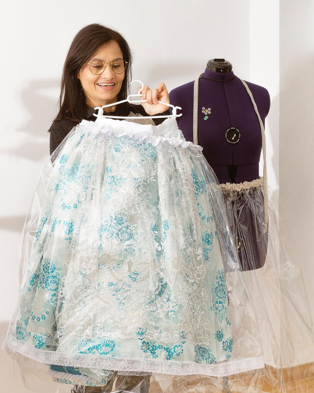 Costurera mostrando chubasquero impermeable para vestido de fallera hecho a medida